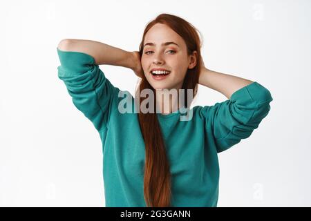 Glücklich unbeschwert Ingwer Mädchen, Ruhe und genießen Sommerferien, halten Sie die Hände hinter dem Kopf, liegend und entspannt, lächelnd zufrieden, weißer Hintergrund Stockfoto