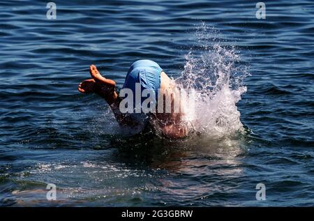 Kiel, Deutschland. Juni 2021. Ein junger Mann springt von einer Schwimmplattform in ein zum Schwimmen gesperrtes Gebiet der Kieler Förde. Auch im Norden beginnt der Sommer mit großer Hitze. Quelle: Axel Heimken/dpa/Alamy Live News Stockfoto