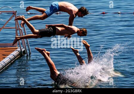 Kiel, Deutschland. Juni 2021. Vier junge Männer springen von einer Schwimmplattform in ein zum Schwimmen gesperrtes Gebiet der Kieler Förde. Auch im Norden beginnt der Sommer heiß. Quelle: Axel Heimken/dpa/Alamy Live News Stockfoto