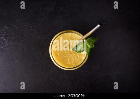 Draufsicht Mango Lassi aus Glas mit Rohr auf dunklem Hintergrund. Traditionelles indisches und pakistanisches Getränk Stockfoto