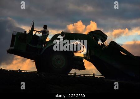 Siehe Alamy Image Ref WR6G0B, um die Art der Landschaft zu sehen, in der diese Maschine arbeitete. Historische 1970er-Jahre Nahaufnahme Archiv Ansicht eines männlichen Fahrers & Maschine in Silhouette arbeiten spät mit dramatischen Wolken am Himmel über das Fahren großer Motor Schaber Erde bewegen schwere Pflanze eine von vielen Kratzen und Transport von Boden zu Böschungen für tiefe Straße Schneiden ein Archivbild auf 70er-Major bilden Bauprojekt für die Tiefbauinfrastruktur auf der neuen M25-Ringautobahn in London im Jahr 1977 in Brentwood Essex England, Großbritannien, in der Nähe der Anschlussstelle 28 Stockfoto