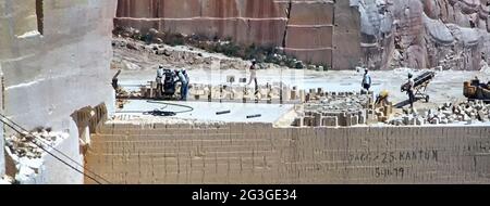 Archivansicht der maltesischen oberflächennahen Minenarbeiter der 1980er Jahre, die über einem Schertropfen einer ungeschützten vernarbten Oberfläche aus Kalkstein mit offenem Guss arbeiten Steinbruch mit Gesundheits- und Sicherheitsprobleme nach Jahren des Betriebs von Scheibensägen Schneidemaschinen & Sägen in weichen Gestein zu In Blöcke für die 80er-Jahre-Baustellen auf der Insel Malta in historischen Archivbild Juni 1981 geschnitten werden Stockfoto