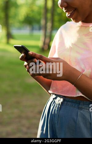 Nahaufnahme einer jungen afrikanischen Frau, die im Freien eine Nachricht auf dem Mobiltelefon tippt Stockfoto