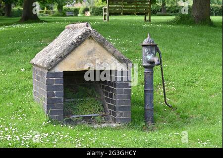 Ehemalige Wasserpumpe auf dem Grün im nördlichen Oxfordshire Dorf Kingham Stockfoto