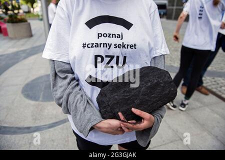 Warschau, Polen, 16/06/2021, Aktivisten halten während des Protestes vor dem Hauptquartier der PZU ein Stück Kohle in der Hand.Umweltaktivisten protestierten vor dem Hauptquartier der PZU in Warschau. Die Powszechny Zaklad Ubezpieczen (PZU) Group ist die größte Versicherungsgesellschaft in Polen und verantwortlich für die Gesundheit und das Leben von über 20 Millionen Polen. Es ist die letzte der großen Versicherungsgesellschaften in Europa, die keine Politik des Abrufenens der bestehenden oder der Aufhebung neuer Investitionen in Minen und Kohlekraftwerke verfolgt hat. PZU versichert Minen, die über 95 % der Kohle in Polen fördern, sowie Kohlekraftwerke, einschließlich Stockfoto