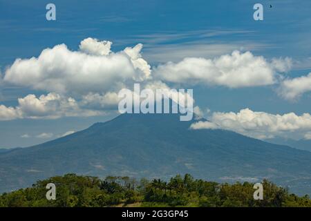 Blick auf den Vulkan Klabat, den höchsten Vulkan Sulawesis, und die umliegende Regenwaldlandschaft, in weiße Wolken gehüllt, Indonesien Stockfoto