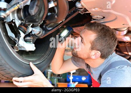 Automechaniker repariert Fahrzeug in einer Werkstatt - Bremsen auf Sicherheit prüfen Stockfoto