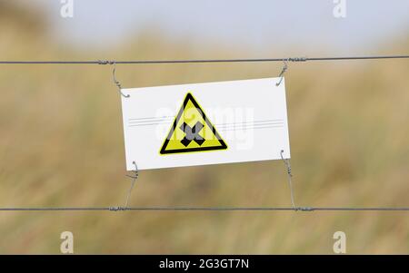 Grenzzaun - Altes Plastikschild mit Flagge Stockfoto