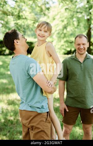 Zwei Eltern von schwulen Familie spielen mit kleinen Mädchen im Park im Freien Stockfoto