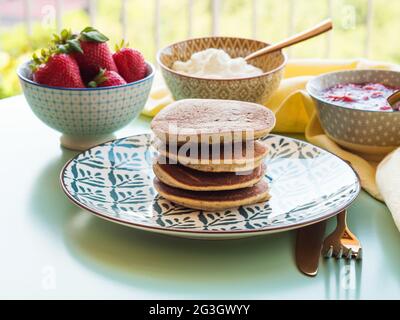 Vegane glutenfreie Bananenpfannkuchen mit Buchweizen, serviert mit milchfreiem Joghurt und Chia-Erdbeermarmelade Stockfoto