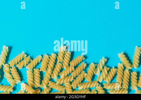 Pasta in Form von Spiralen auf blauem Hintergrund. Draufsicht. Stockfoto