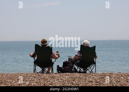 Die Menschen sahen, wie sie an einem warmen und sonnigen Tag im Juni 2021 in Stühlen am Strand von Bognor Regis saßen Stockfoto