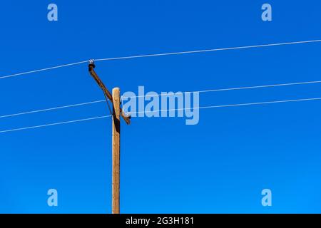 Hölzerner Pfosten mit Drähten und klarem blauen Himmel Stockfoto