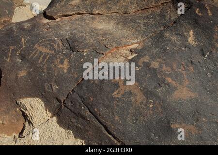 Uralte Felszeichnungen von Tieren wie Kamel, Gazelle und frühen arabischen Buchstaben in der Patina eines Kalksteinfelsen in Nachal Zin, der Negev-Wüste. Stockfoto