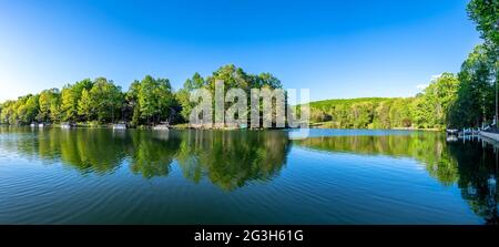 Das malerische Panorama des Lake Dartmoor in Tennessee zeigt eine sehr ruhige, glasige Seenoberfläche mit reichen, gesunden Eichen, die die Küste säumen. Stockfoto