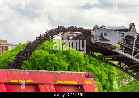 Die Kaltfräsmaschine der Straße entfernt den alten Asphalt und die Beladung in einen Muldenkipper. Reparatur des Asphaltbelags der Straße Stockfoto