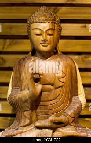 Beleuchteter Buddha aus Holz, der auf einem hölzernen Hintergrund meditiert Stockfoto