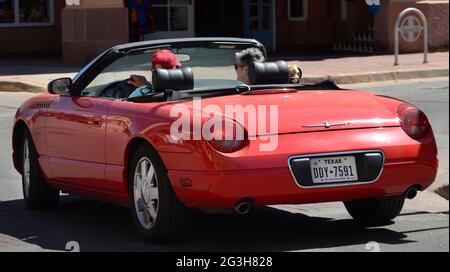 Ein Paar, das aus Texas nach Santa Fe, New Mexico, reist, fährt in ihrem Ford Thunderbird Cabriolet eine Straße entlang. Stockfoto