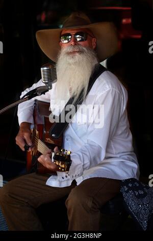 Johnny Lloyd, ein bekannter lokaler Straßenmusiker und Straßenmusiker, tritt auf einem Bürgersteig in Santa Fe, New Mexico, auf. Stockfoto