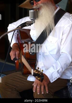 Johnny Lloyd, ein bekannter lokaler Straßenmusiker und Straßenmusiker, tritt auf einem Bürgersteig in Santa Fe, New Mexico, auf. Stockfoto