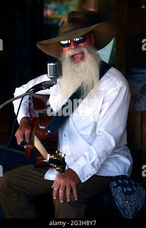 Johnny Lloyd, ein bekannter lokaler Straßenmusiker und Straßenmusiker, tritt auf einem Bürgersteig in Santa Fe, New Mexico, auf. Stockfoto