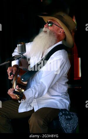 Johnny Lloyd, ein bekannter lokaler Straßenmusiker und Straßenmusiker, tritt auf einem Bürgersteig in Santa Fe, New Mexico, auf. Stockfoto