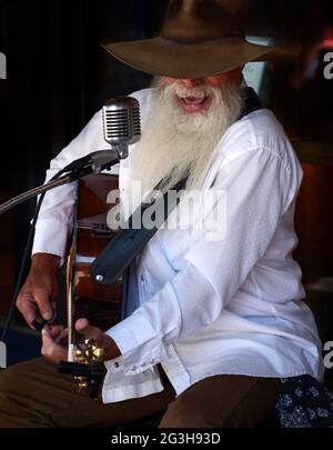 Johnny Lloyd, ein bekannter lokaler Straßenmusiker und Straßenmusiker, tritt auf einem Bürgersteig in Santa Fe, New Mexico, auf. Stockfoto