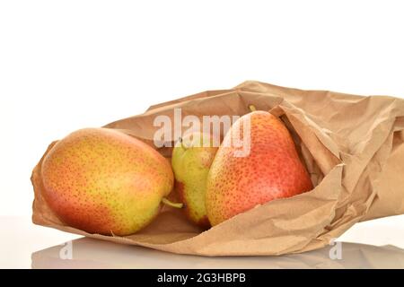 Drei reife gelb-rote Birnen in einer Papiertüte, Nahaufnahme, auf weißem Hintergrund. Stockfoto