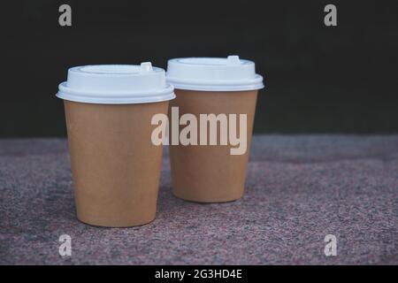 Zwei Tassen Kaffee zum Mitnehmen im Park auf der Marmorbank. Stockfoto