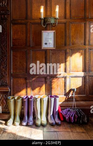 Gummistiefel und Regenschirme am Vordereingang des Manor House Hotel, Castle Combe, Wiltshire, England, Großbritannien Stockfoto