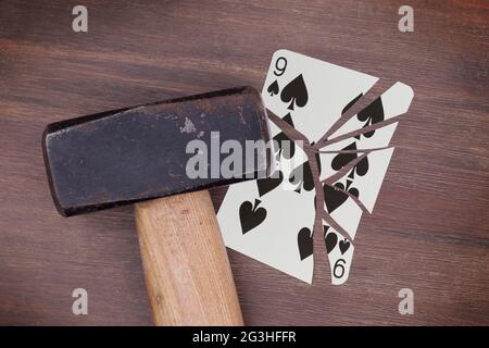 Hammer mit einer zerbrochenen Karte, neun Pik Stockfoto