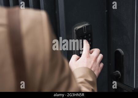 Beschnittene Ansicht des Mannes, der die Taste auf der Gegensprechanlage drückt Stockfoto