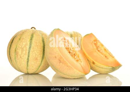 Ein Schnitt in zwei Hälften und zwei ganze duftende, saftige Bio-Melonen, Nahaufnahme, vor weißem Hintergrund. Stockfoto