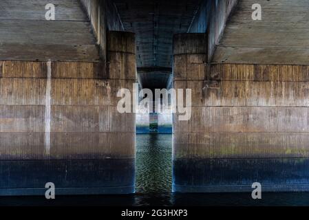 Blick auf die Betonsäulen unter einer Brücke als abstrakter symmetrischer Hintergrund in der Bremer Weserpromenade (Schlachte) Stockfoto