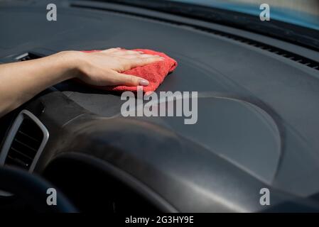 Frau wischt das Armaturenbrett des Autos von Staub ab. Stockfoto