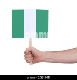 Hand hält kleine Karte - Flagge von Nigeria Stockfoto