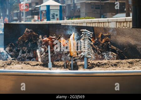 In einem Restaurant am Strand von Malagueta, Málaga, Spanien, werden bei einem behelfsmäßigen Holzfeuer-Barbecue verschiedene Meeresfrüchte gekocht Stockfoto