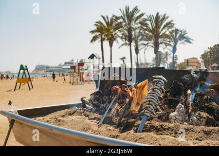 In einem Restaurant am Strand von Malagueta, Málaga, Spanien, werden bei einem behelfsmäßigen Holzfeuer-Barbecue verschiedene Meeresfrüchte gekocht Stockfoto