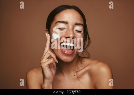 Nahaufnahme der glücklichen jungen Frau Anwendung Creme für Vitiligo. Portrait einer fröhlichen jungen Frau mit Vitiligo Make-up. Stockfoto