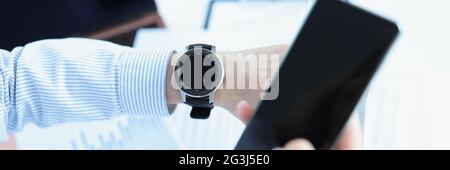 Der Mensch hält das Smartphone in der Hand und schaut smart an Sehen Sie Stockfoto