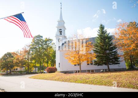 Kirche und amerikanische Flagge im Herbst Laub, Centre Sandwich, New Hampshire Stockfoto