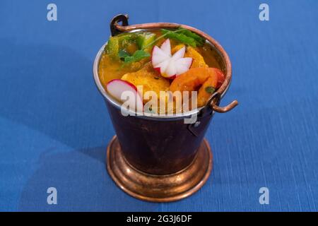 Draufsicht auf ein köstliches Huhn balti mit indischen Gewürzen auf blauem Hintergrund in einer Metallschale. Stockfoto