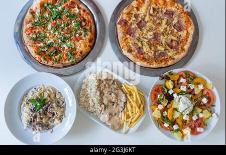 Vielfalt an verschiedenen kulturellen Gerichten in der Tabelle der indischen Lebensmittelteller Pizza, Salat, Reis, Fleisch, Gemüse. Das Panorama des Essens. Draufsicht Stockfoto