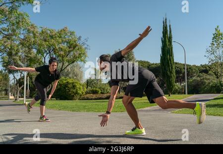 Persönlicher Fitnesstrainer für das Funktionstraining, coacht einen Kunden für das Rollschuhfahren. Zu den Parks im Sommer. Stockfoto