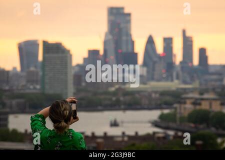 Eine Frau fotografiert die Skyline von London bei Sonnenuntergang vom Greenwich Park in London aus. Der Mittwoch könnte der heißeste Tag des Jahres sein, da Teile Großbritanniens sich bei 30 Grad Hitze sonnen werden. Bilddatum: Mittwoch, 16. Juni 2021. Stockfoto
