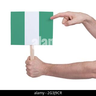 Hand hält kleine Karte - Flagge von Nigeria Stockfoto