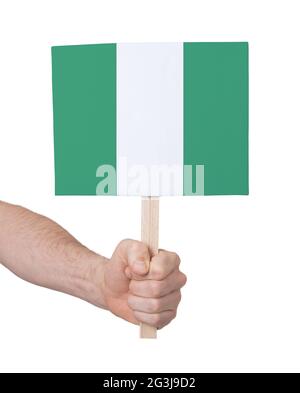Hand hält kleine Karte - Flagge von Nigeria Stockfoto