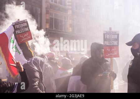 LONDON, ENGLAND - 15. Mai 2021: Demonstranten bei einer Demonstration für Palästina inmitten von Rauchflackernebel Stockfoto