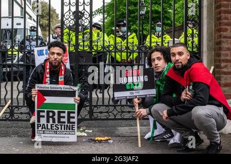 LONDON, ENGLAND - 15. Mai 2021: Demonstranten posieren mit einer verbrannten israelischen Flagge bei einem Marsch für Palästina-Demonstration Stockfoto
