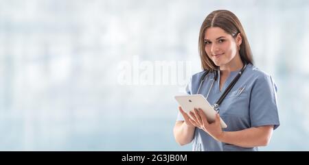Panoramafoto einer jungen Krankenschwester im Krankenhaus, die auf dem Tablet mit Stethoskop am Hals herumhing. Stockfoto